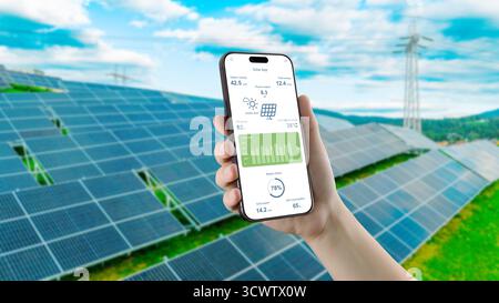 Hand holding smartphone with solar monitoring app in front of photovoltaic panels Stock Photo