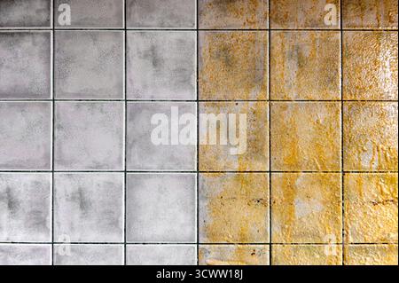 Tiles on the kitchen wall. Tiled wall half clean and half dirty, with a striking contrast. Half of the tiles are dirty, the other half are clean. Stock Photo