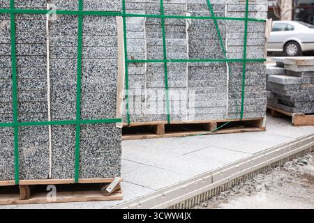 Packs of new paving granite tiles stacked on pallets for laying on the road Stock Photo