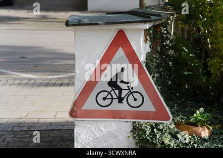 Bicycle warning traffic sign mounted on a wall in a quiet German neighborhood, promoting cycling safety and awareness.Munich,Germany Stock Photo