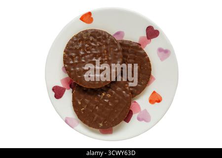 3 Three gingerbread flavour wheatmeal biscuits covered in milk chocolate on plate with hearts on isolated on white background - Mcvitie's Mcvitie Stock Photo