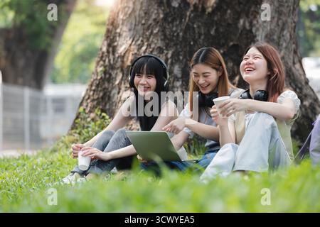 Group Of Young Asian Students Collaborating Outdoors at University. Teamwork and Knowledge Sharing. Asian Students Engaged in Collaborative Learning Stock Photo