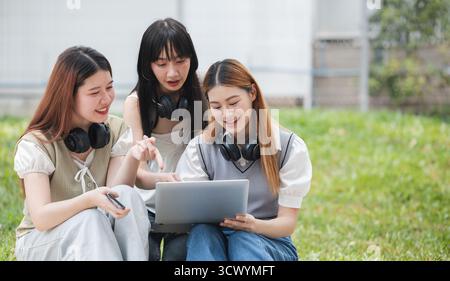 Group Of Young Asian Students Collaborating Outdoors at University. Teamwork and Knowledge Sharing. Asian Students Engaged in Collaborative Learning Stock Photo