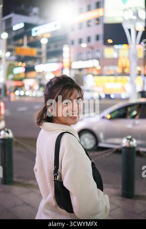 Asian woman smiling in city street at night, Concept of urban nightlife Stock Photo