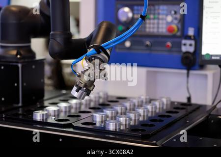 Robot manipulator loads workpiece in CNC machine. Selective focus. Stock Photo