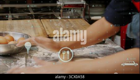 Cook's forearms kneading dough on wooden countertop in kitchen, with egg bowl and overlay icons Stock Photo