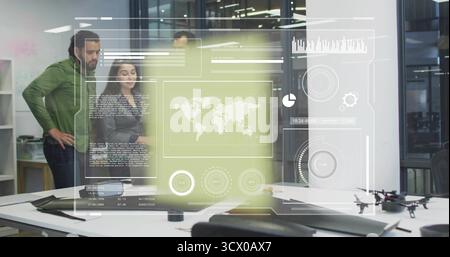 Analyzing data overlays collaborating around desk in office, with laptop tablet drone and projector Stock Photo