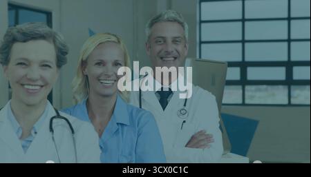 Group of three medical staff standing in hospital corridor, with stethoscopes and cardboard boxes Stock Photo