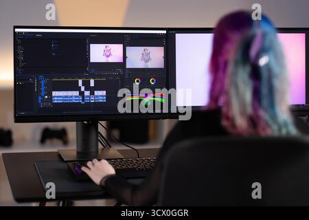 Young woman editing video content on a professional workstation Stock Photo