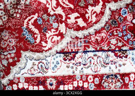 Traditional patterned rugs and woven carpet textures in rich red, blue and cream colors, showing ornate decorative textile craftsmanship Stock Photo