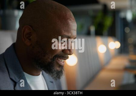 Closeup side view of bald mature businessman smiling while deep in thought in office Stock Photo