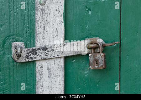 Weathered metal padlock and latch on an aged green door in Zellerndorf, Lower Austria Stock Photo