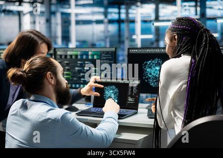Data center coworkers collaborating, managing AI training datasets. IT staff members working together overseeing machine learning in server farm supporting scalable equipment for AI apps Stock Photo
