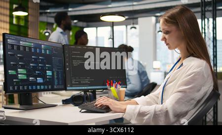 Cheerful startup manager satisfied with progress oj junior dev learning how to use machine learning tech. Team leader doing fist bump with intern in office, satisfied with work done, camera A Stock Photo