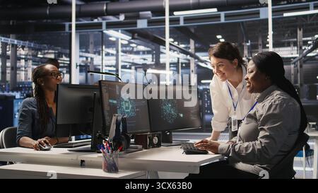 Cheerful data center technicians satisfied with results after collaborating on AI automation deployment. Happy server hub coworkers adjust machine learning configurations, working together, camera A Stock Photo