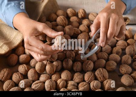 Female hands with walnuts and nutcracker at wooden table Stock Photo
