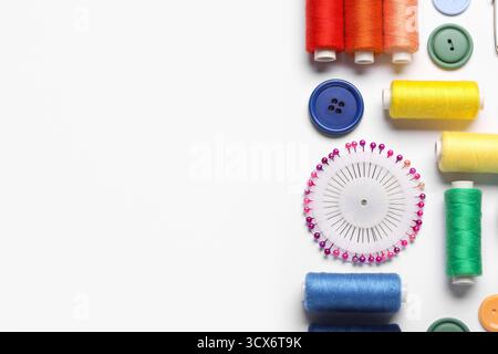 Composition with different thread spools, ball pins and buttons on white background, closeup Stock Photo