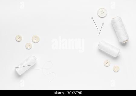 Spools of thread with buttons and ball pins on white background Stock Photo