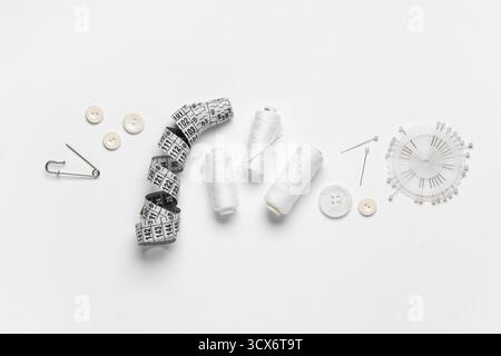 Spools of thread with ball pins, buttons and measuring tape on white background Stock Photo