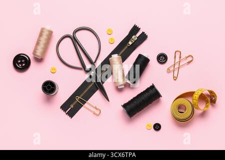 Composition with thread spools, scissors and buttons on pink background Stock Photo