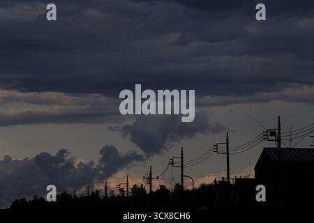 Cloudy dusk sky over telegraph wires and houses in Tsuruma, Yamato, Kanagawa, Japan. Stock Photo