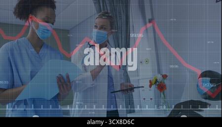 Reviewing scrub-clad nurse and doctor pointing at tablet at bedside, with chart and ECG overlay Stock Photo