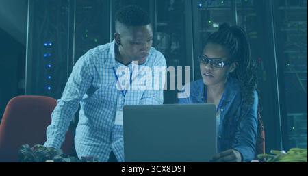 Two IT professionals troubleshooting network equipment in data center, with laptop, server racks Stock Photo