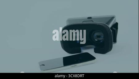 Displaying virtual reality headset resting on studio tabletop, with smartphone lying beside headset Stock Photo