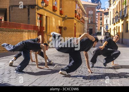 Group of young and energetic hip hop dancers moving in a synchronized street performance on a cobbled stone street in an old european city, showcasing Stock Photo