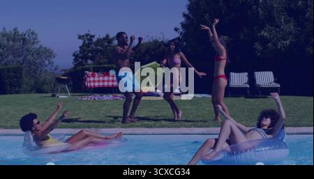 Floating friends in swimsuits on float tubes and dancing at backyard pool, with picnic table Stock Photo