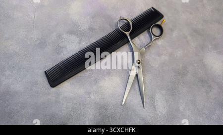 Special hairdressing scissors and comb. Professional equipment. On a gray background. Copy space Stock Photo
