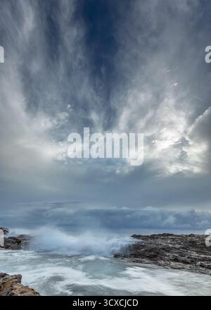 Dawn at Snapper Rocks, located on the Gold Coast of Australia, reveals stormy seas crashing against jagged, rocky shores. Stock Photo