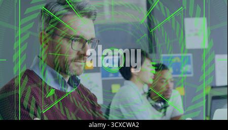 Maroon sweater man typing on computer at office desk, with sticky notes, green overlay, copy space Stock Photo