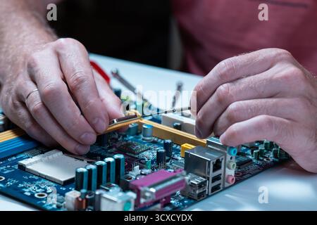 A master repairs a motherboard from a computer Stock Photo