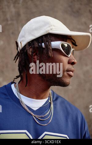 Young Adult Black Man Wearing Sunglasses and Cap Standing Outdoors Stock Photo