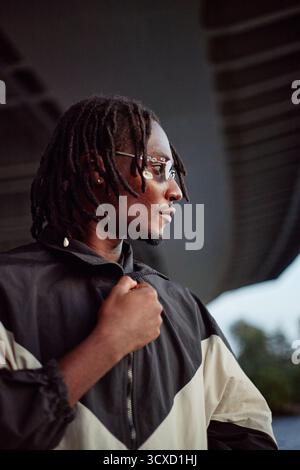 Young Adult Black Man Standing Outdoors Looking Away with Thoughtful Expression Stock Photo