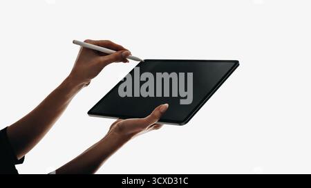 A close-up of hands using a stylus on a sleek black tablet screen, highlighting digital interaction and creativity. Perfect for themes of technology, Stock Photo