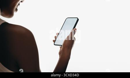 Close-up of a woman holding a smartphone and interacting with its screen in a minimal setting focusing on modern technology and connection Stock Photo