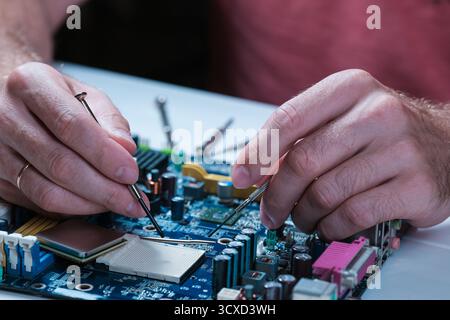 A master repairs a motherboard from a computer Stock Photo