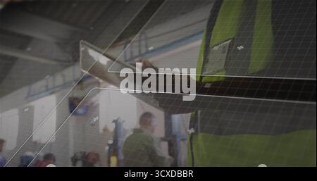 Holding technician tapping tablet computer in terminal hall, with safety vest and badge, copy space Stock Photo