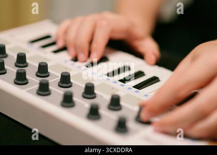 A close-up of a musicians hands interacting with a MIDI controller synthesizer keyboard. Electronic music production, ideal for themes of sound design Stock Photo
