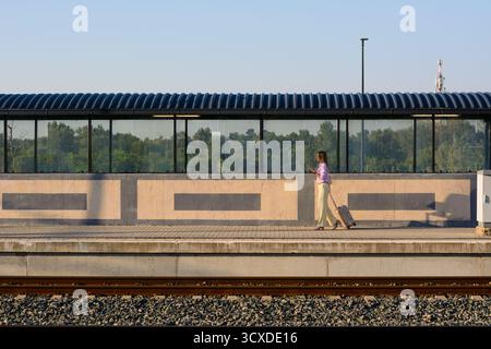 Elegant businesswoman walking confidently with suitcase and using mobile at the train station. Copy space for your text or advertisement. Stock Photo