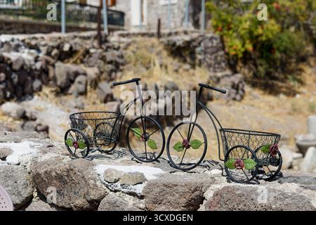 Decorative metal bicycle planters on a stone wall outdoors. Stock Photo