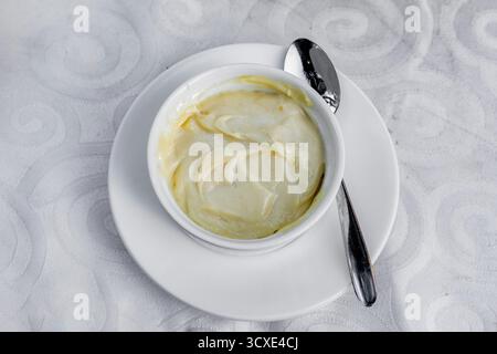 Delicious creamy sauce served in a small white bowl on a white plate Stock Photo