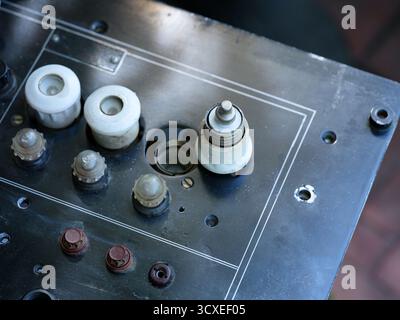 Old black electrical panel with white ceramic plug fuses and small lamps Stock Photo