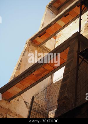 Old building ruins in the historic center of Trapani under bright sunlight, showing decayed walls and exposed brick structure Stock Photo