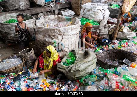 October 14, 2025, Dhaka, Bangladesh: Workers sort used plastic bottles in a recycling factory in Dhaka, Bangladesh. They help to prevent the bottles from being discarded, sent to landfill, where they can take 1,000 years to biodegrade, or incinerated, which produces toxic fumes. The emission of CO2 and other greenhouse gases will be reduced if recycling takes place in the production of new plastics. This small yet significant act supports environmental sustainability by promoting a responsible cycle of reuse, reducing the strain on natural resources, and safeguarding our ecosystem for future g Stock Photo