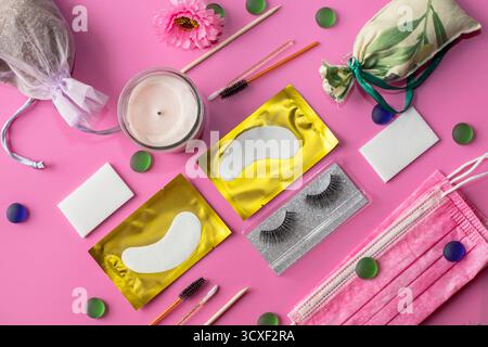 Professional eyelash extension tools and eye patches arranged on pink background with flower and beauty accessories Stock Photo