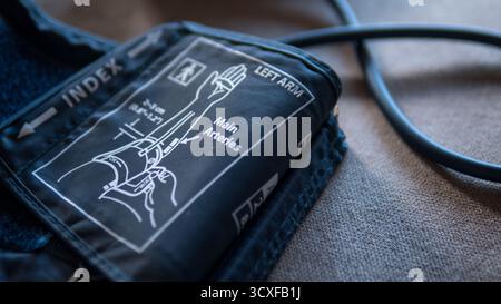 Close-up of a blood pressure cuff with anatomical diagram and labeled instructions for measuring blood pressure on the left arm. Stock Photo