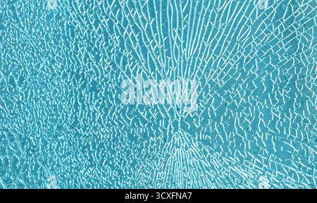 Shattered blue tempered glass showing numerous cracks and fractures, creating an abstract texture Stock Photo